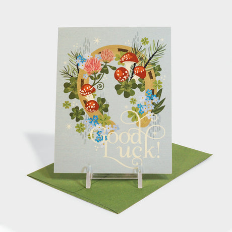 Greeting card with illustration of a horseshoe decorated with clovers and other foliage.