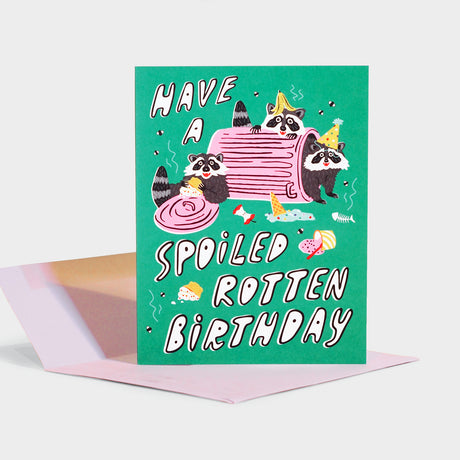 Greeting card with illustration of raccoons eating from an overturned trash can