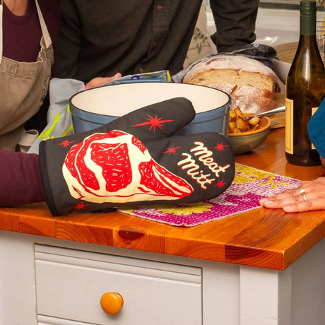 Person holding a pot with the Meat Mitt oven mitt. Photo © Blue Q