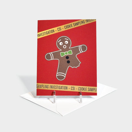 Greeting card featuring a classic ginger bread cookie with its leg eaten. Gold foil-stamped 'investigation tape' appears above and below with "Cookie Sampling Investigation - CSI" repeated.