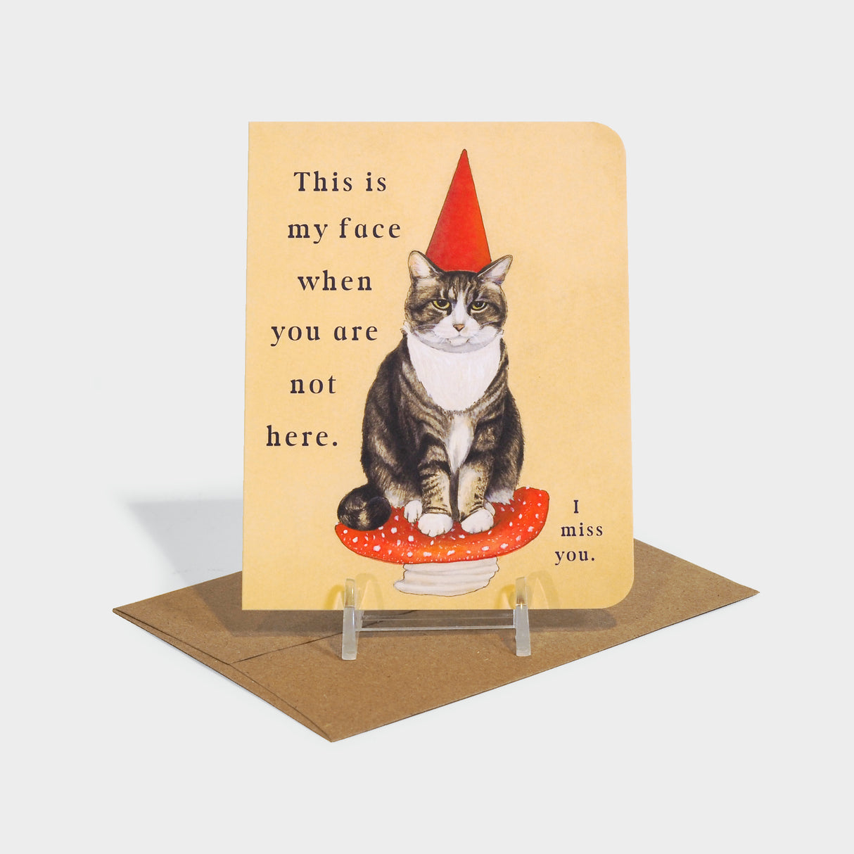 Greeting card with image of a cat in a gnome hat sitting on a mushroom.