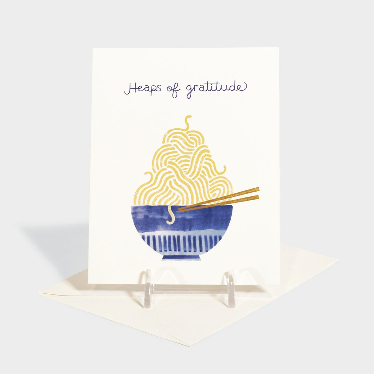 Greeting card with an illustration of a tall bowl of noodles. Inside also features a small illustration of chopsticks holding a noodle.