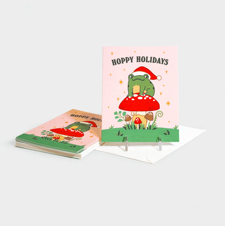 Greeting cards with an illustration of a frog in a Santa hat sitting atop a mushroom.