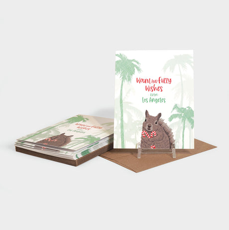 Greeting cards with a squirrel holding candy canes on a background of palm trees.