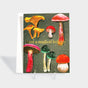 Greeting card with illustrated mushrooms and sprinkled snow. Features gold foil-stamped text.